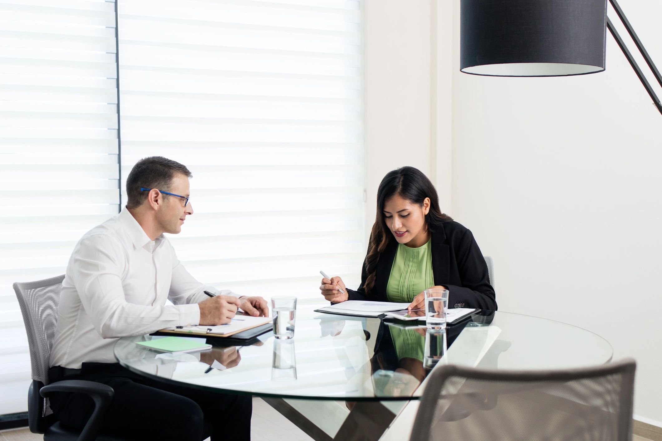 Two executives in a one-to-one meeting reviewing documents